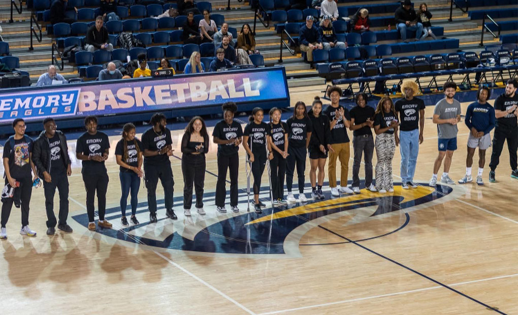 Photo: Emory basketball teams standing in a single line facing camera on home court